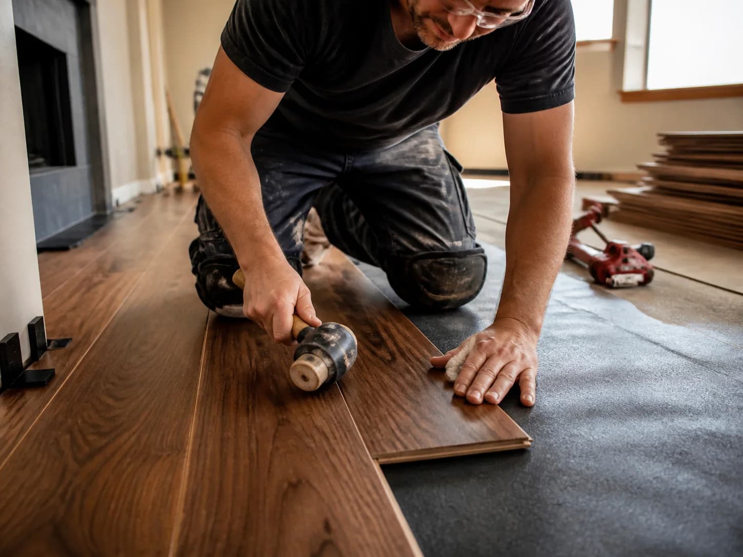 Representative scene of a craftsperson fitting walnut-toned flooring planks