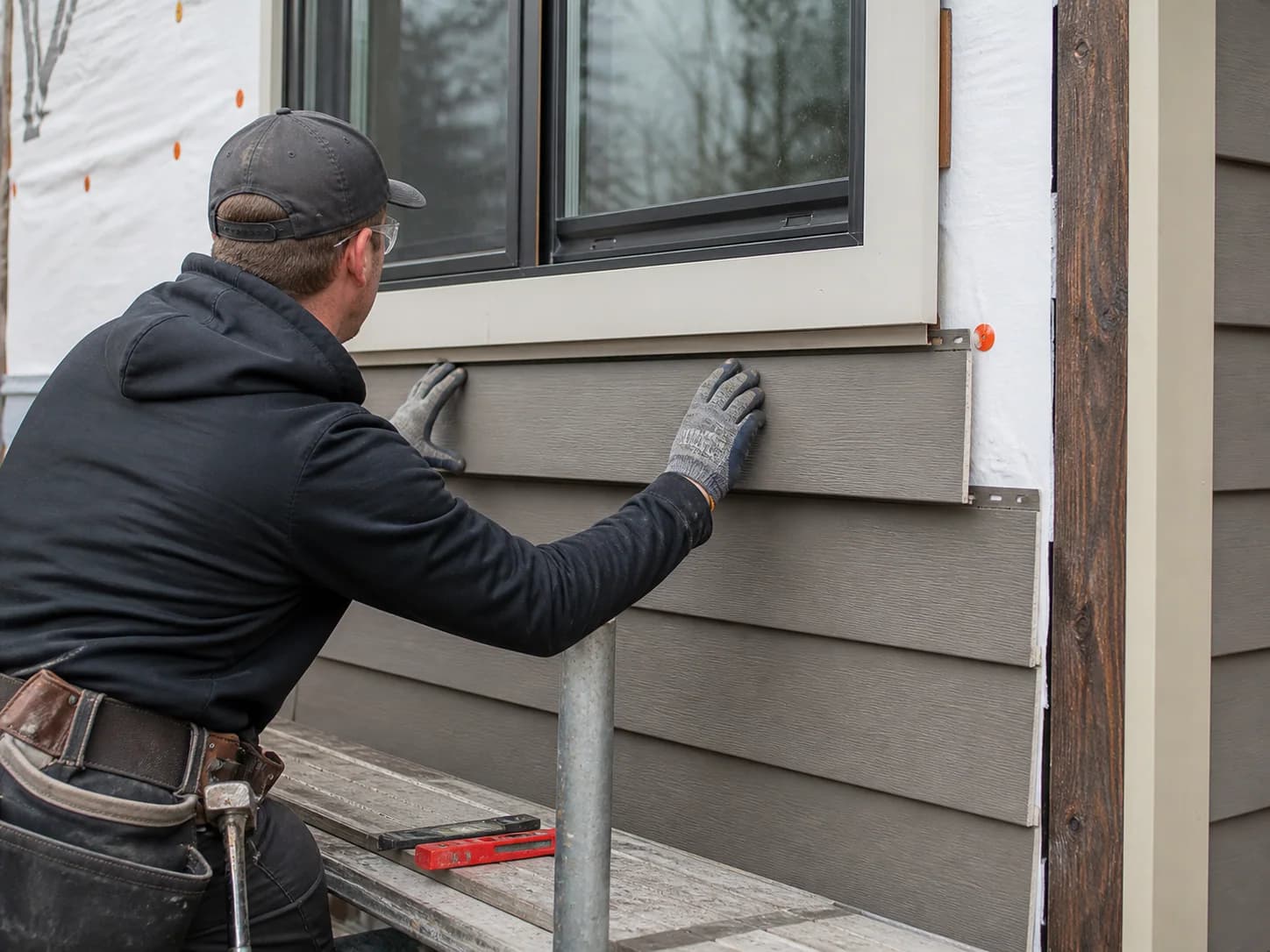 Representative scene of a craftsperson aligning siding beneath a window